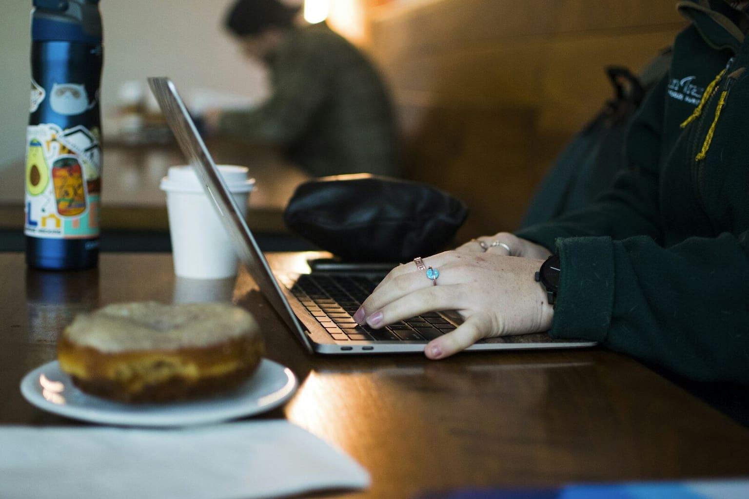Person working on a laptop at a cafe table with coffee